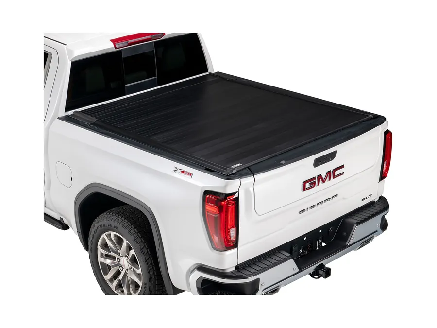 Retractable aluminum bed cover closed flush over the bed of a white full-size pickup