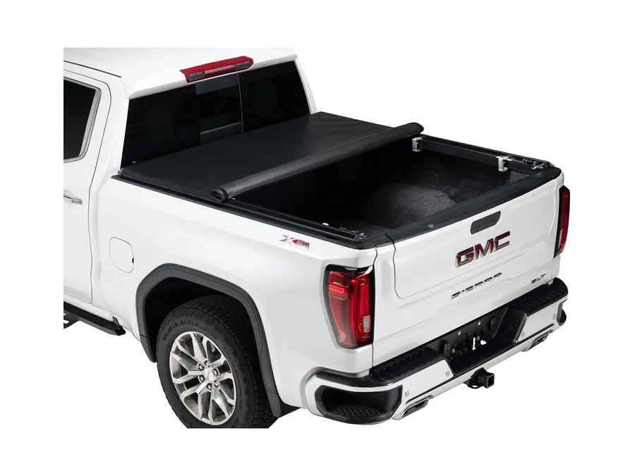 Soft roll-up bed cover rolled forward to open the bed of a white full-size pickup